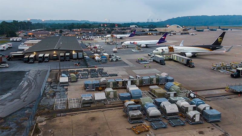 Transport containers being loaded onto trucks from cargo airplanes.