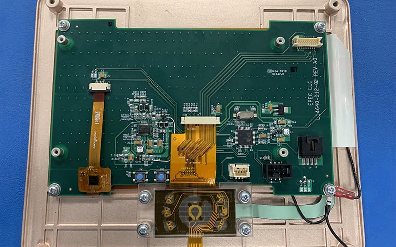 Rear side of HMI with PCBA and flex circuits exposed.